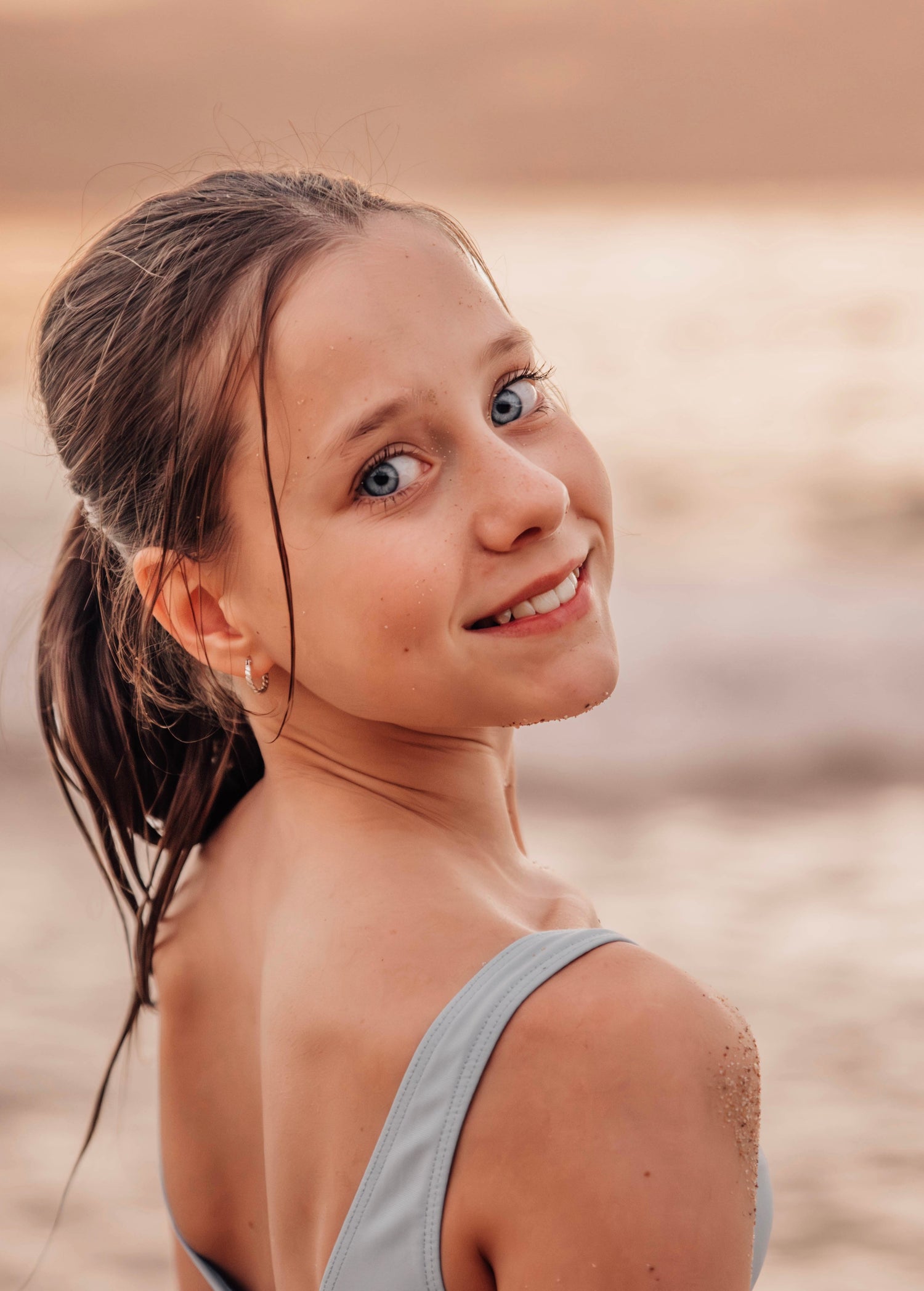 Young girl with a ponytail standing on a beach